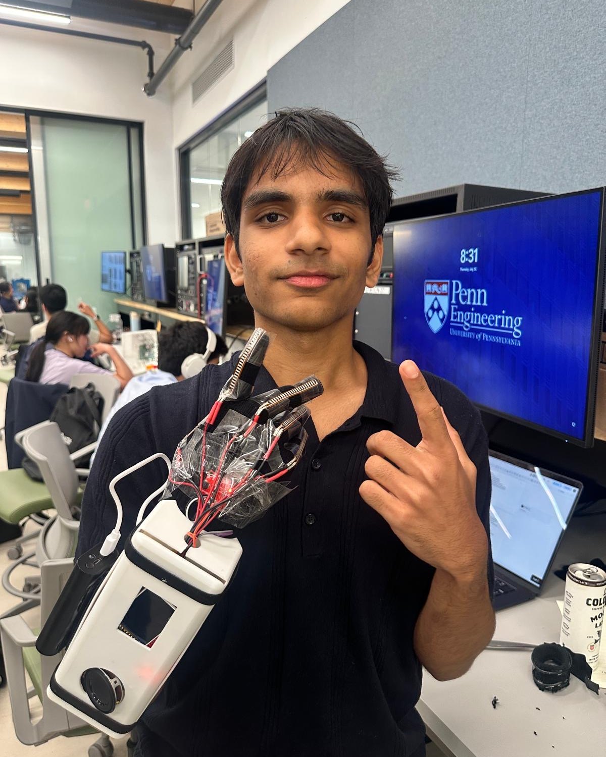Ishaan holding a sensor glove he built, in a Penn Engineering lab